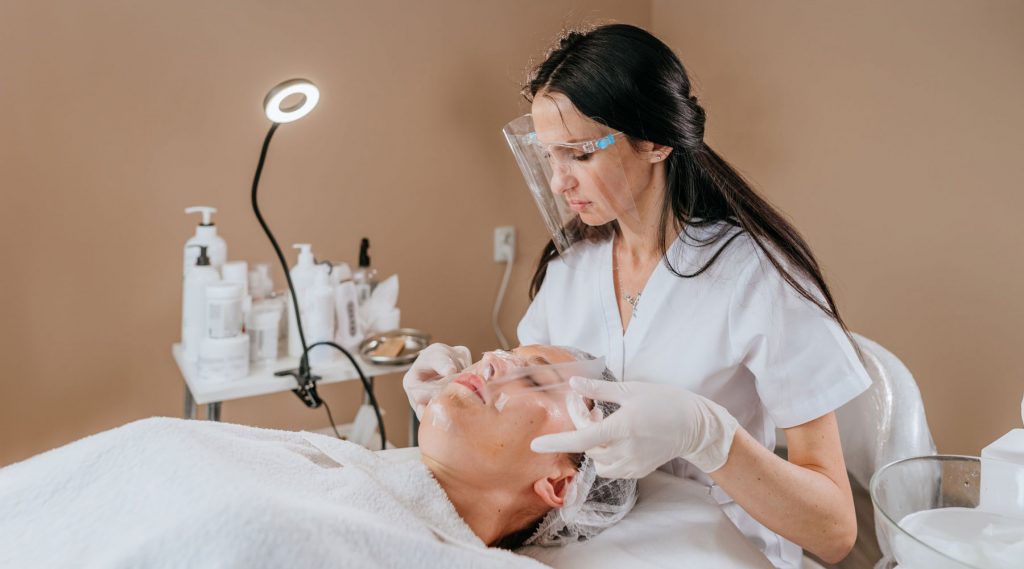 Beauty specialist doing facial treatment for female customer